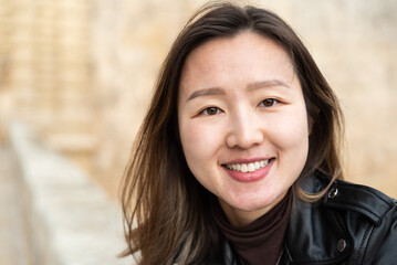 Head shot portrait of an attractive 29 year old Asian American girl against a yellow wall