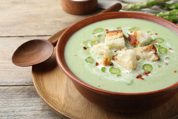 Delicious asparagus soup with croutons served on wooden table, closeup