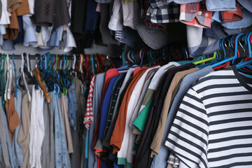 Hangers with stylish clothes on racks as background, closeup. Fast fashion