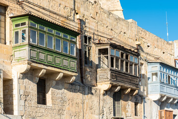 Malta, Valletta, Valletta, Malta - 01 07 2022: Historical houses with wooden bow windows and terraces in a narrow street