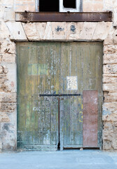 Valletta, Malta - 01 07 2022: Worn wooden garage door of an old building