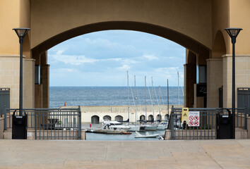 San Julian, Malta - 01 07 2022: See through of the gate of the Portomaso private bay with the harbor and sea in the background