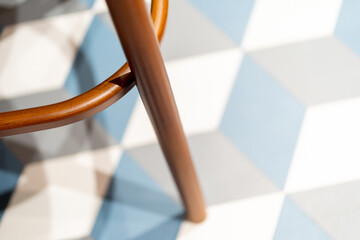 Moder wooden chair or stool leg against blue and white tiled floor 