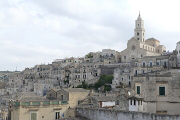 Fototapeta na wymiar Cathedral with white sandstone facade and bell tower on the top of the hill in Matera