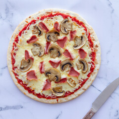 Prosciutto and mushroom pizza on a marble background