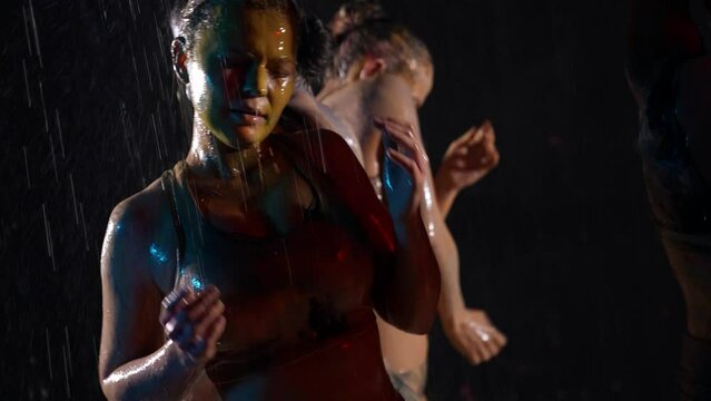 beautiful and sensual women are dancing in water flows and washing out paints from bodies