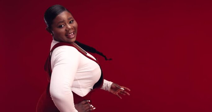 happy young african american woman with long hair braid whirling around on red background