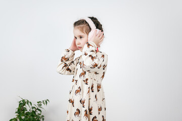 The use of technology. A little girl in a home interior listens to music with headphones.