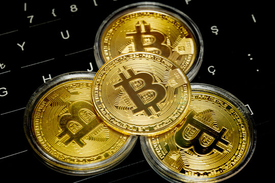Symbolic gold bitcoin coins with bitcoin symbol on keyboard keys. Bitcoin coin in the middle in selective focus. Cryptocurrency, stock market, blockchain, digital money, investment, saving concept.