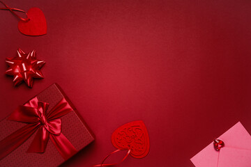 Red gift box with red ribbon, hearts and pink envelope on red background, romantic valentine's day gift for lovers.