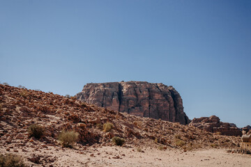 Fototapeta na wymiar Mountain of red sandstone. Bushes of thorns in the desert. Mountain landscape in Jordan. Jordan, Middle East
