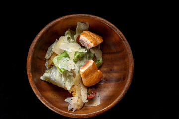 Caesar Salad with Grilled Salmon on wooden Plate Isolated. Salad with Red Fish Fillet, Mini Baguette Crackers.