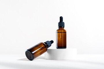 Glass dropper bottles with a pippette with black rubber tip on the white circle podium background. Nature Skin concept. Organic Spa Cosmetics. Trendy concept.