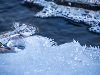 Close-up of ice on a cold November morning starting to form on the surface of the water in a creek with air bubbles frozen in the ice.