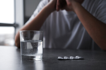 sick woman drinking a pill with a glass of water