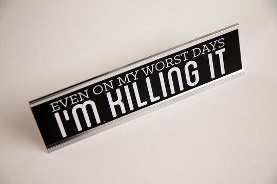 Even on my worst days I am killing it metal black and silver sign on a white shelf