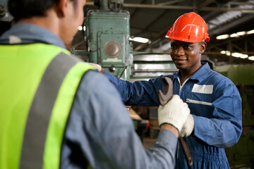 african technician giving or sending wrench to worker for fixing a machine