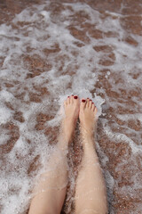 Travel concept - Woman's legs on beautiful tropical beach with pebble sand. Feet on sand and wave in summer time. girl barefoot in ocean water on vacation travel. Feel happy and relax. copy space.