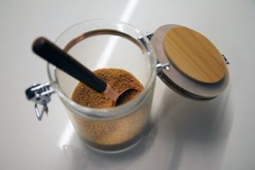 Close up of a isolated glass and wood cane sugar jar with a copper and wood spoon