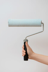 Hand holding paint roller isolated on white background.