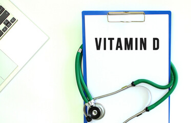 Stethoscope and clipboard with VITAMIN D text on white sheet of paper.