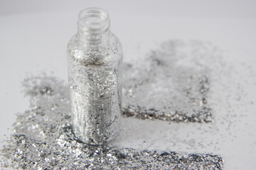 Naklejka na ściany i meble Silver confetti in a transparent bottle on a white background