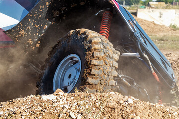 An off-road car is trying to drive out of a deep hole. Close-up.