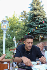 Handsome young boy eating at a restaurant in greenery. Food and eating concept.	
