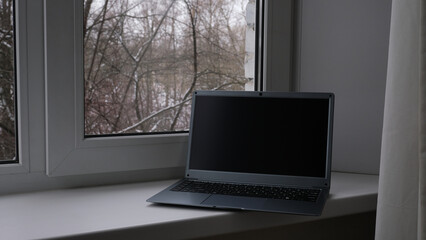 Open laptop on the table by the window
