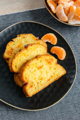Homemade mandarin cake and tangerine on a plate.