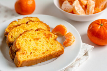 Homemade mandarin cake and tangerine on a plate.