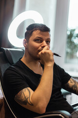 professional man with a tattoo on his arms holds a pen and thinks about a creative idea with a...