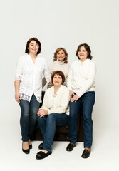a cute grandmother sits on an armchair with her daughters and has fun on a white background.grandmother with her daughters. pensioner with women on white background
