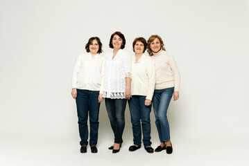 Fototapeta premium grandmother with daughters stands in full growth on a white background. lovely family. group of women of different ages.