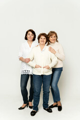 Obraz premium beautiful grandmother smiles being on a white background with her daughters. group of happy women. grandmother hugs her daughter. family day