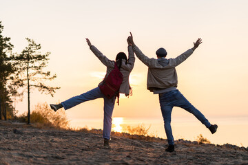 Back view of the caucasian couple holding hands of each other and looking at the sunset. Traveling concept