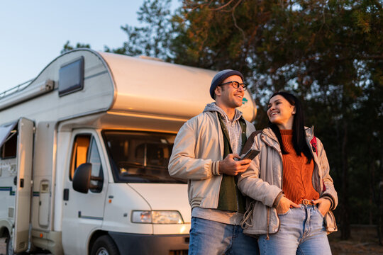 Romantic couple embracing each other while standing at the nature. Warm clothes on, autumn time. In background forest and car