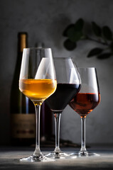 Wines assortment. Red, white, rose wine in glasses and bottles on gray table background. Wine bar, shop, tasting concept