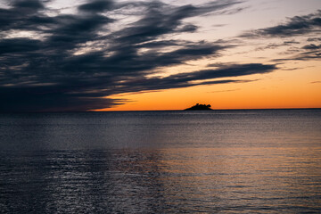 Fototapeta premium Amazing sunset above the distant island off the Rovinj shore with rain clouds approaching over horizon