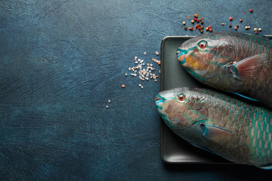 Fresh raw parrot fish cooking on blue stone background