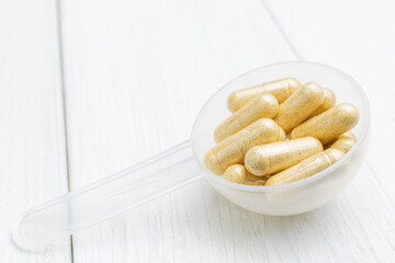 Yellow herbal capsules in a plastic spoon, medication treatment, alternative medicine, close-up view