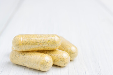 Yellow herbal capsules on white table, medication treatment, alternative medicine, close-up view