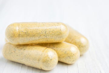 Yellow herbal capsules on white table, medication treatment, alternative medicine, close-up view