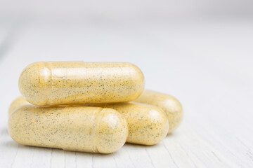 Yellow herbal capsules on white table, medication treatment, alternative medicine, close-up view