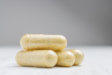 Yellow herbal capsules on white table, medication treatment, alternative medicine, close-up view