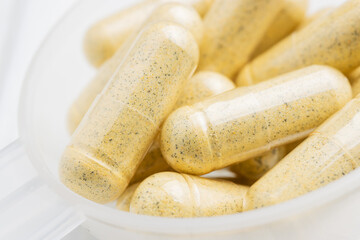 Yellow herbal capsules in a plastic spoon, medication treatment, alternative medicine, close-up view