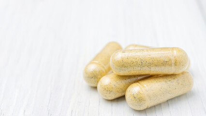 Fototapeta na wymiar Yellow herbal capsules on white table, medication treatment, alternative medicine, close-up view