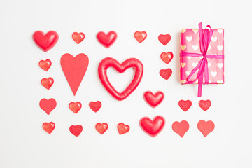 Flat lay valentines day pattern with gift box and red hearts on a white background. Valentines day greeting card