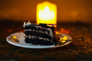 A selective focus of a piece of cold cake against a candle light background.