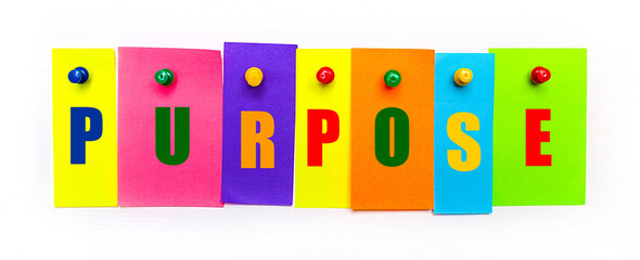 On a white background, buttons are used to fix bright multi-colored strips of paper with the text PURPOSE